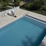 Piscine avec liner gris clair et margelles en pierres Prieuré