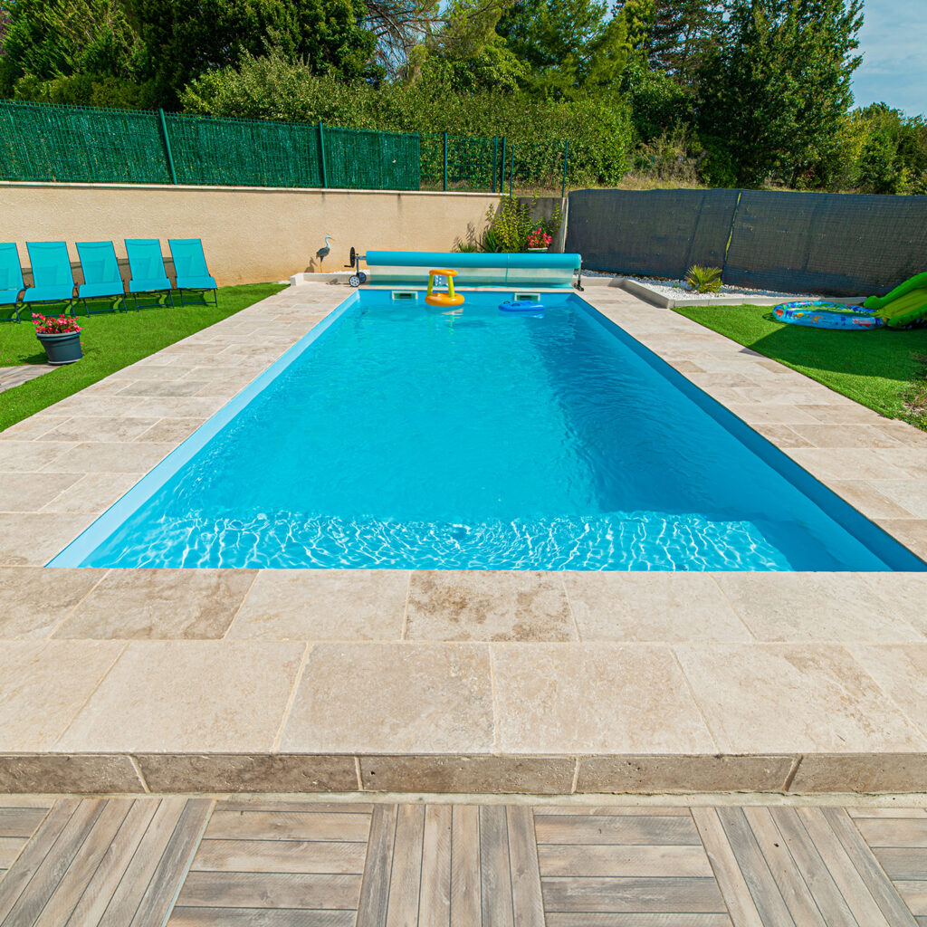 Piscine familiale coque bleu, margelles en pierre naturelle