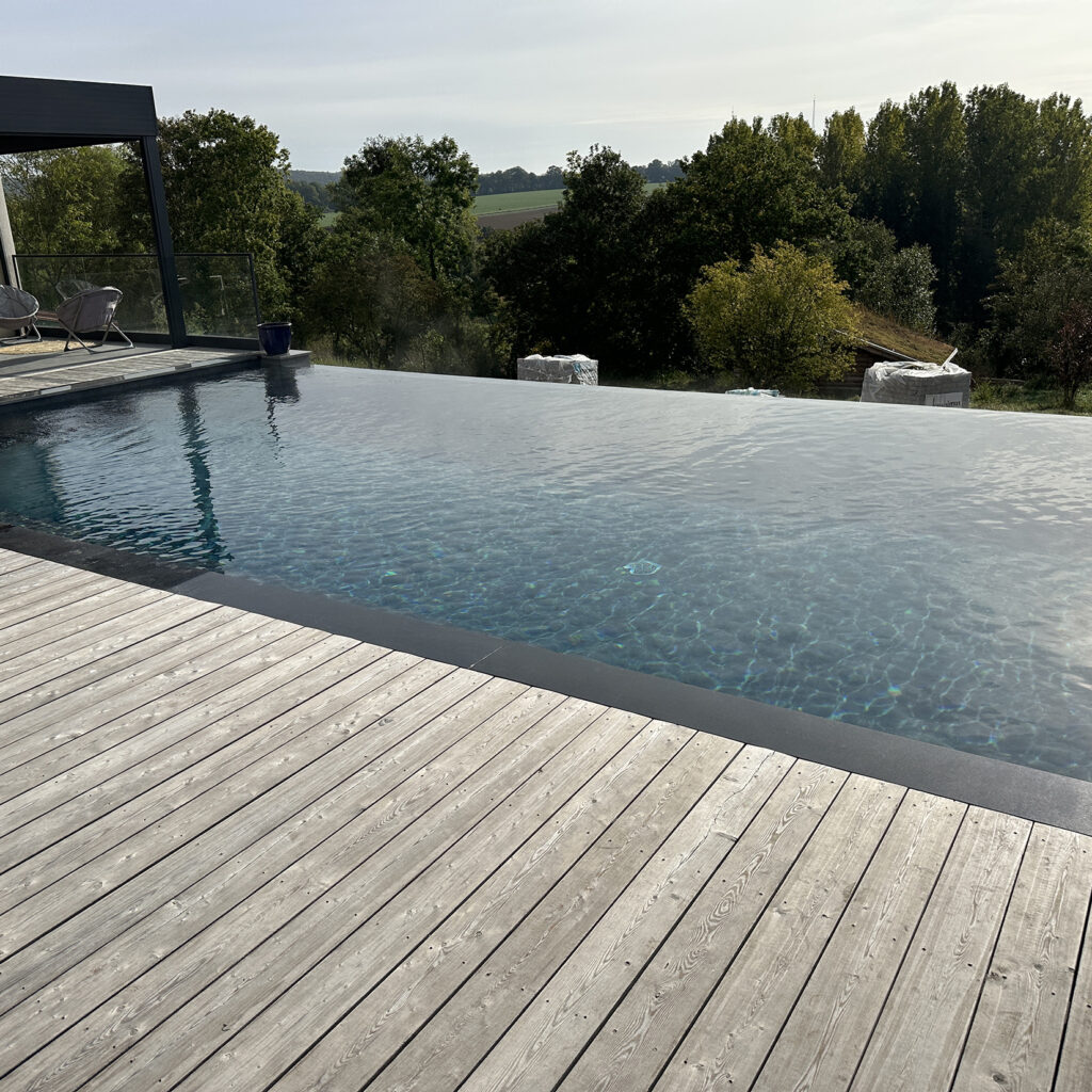 Piscine à débordement avec plage en bois