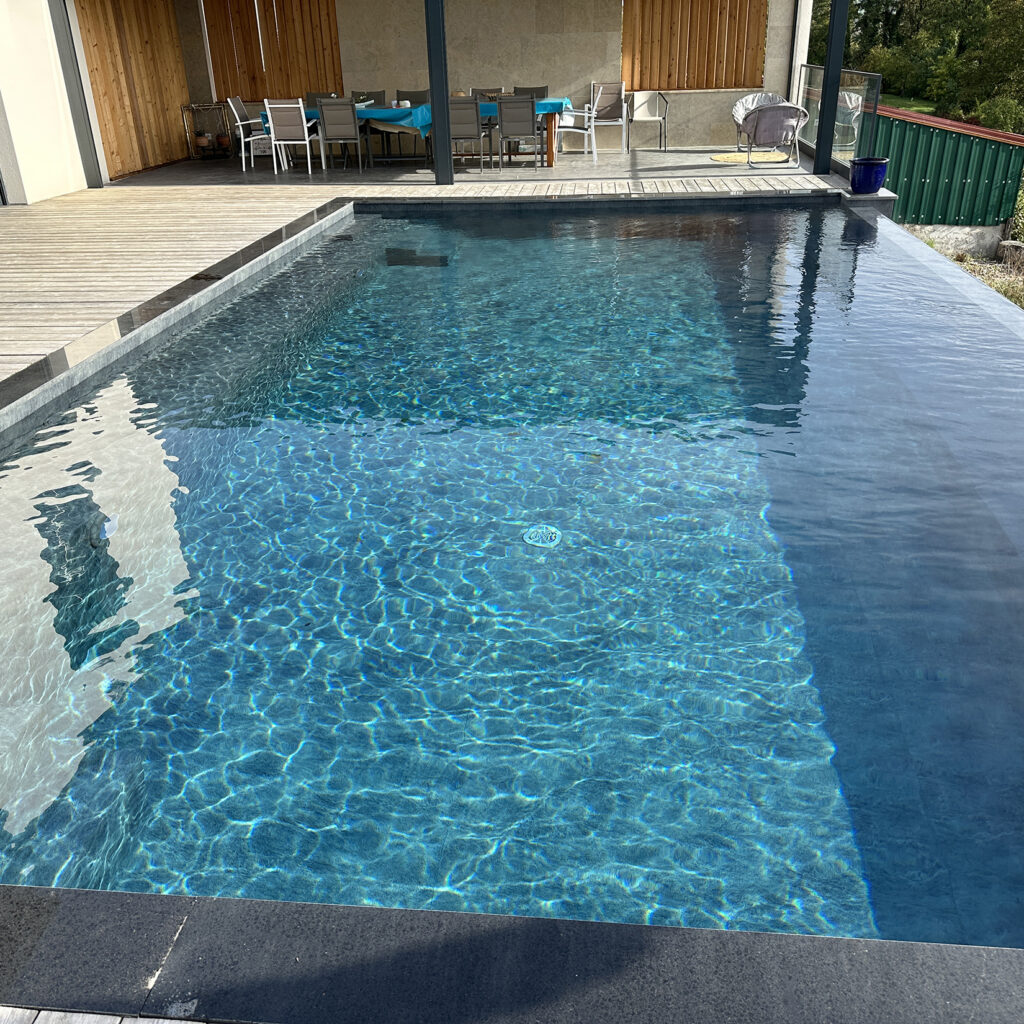 Piscine extérieure à débordement avec plage en bois